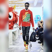 a man in a red sweater walking down the runway