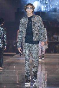 a model walks down the runway wearing a camouflage jacket and pants