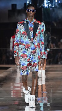 a man in a colorful suit walking down the runway