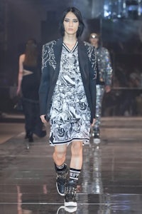 a model walks down the runway wearing a black dress and black boots