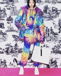 a woman in a tie dye outfit standing in front of a wall