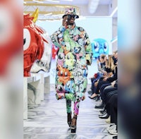 a model walks down the runway in a colorful coat and hat