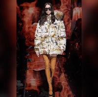 a model walks down the runway wearing a fur coat and thigh high boots